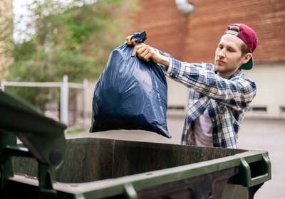 Man taking trash bag to dumpster