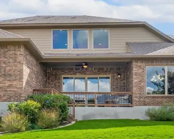 Exterior view of a modern brick house with a patio and green lawn.