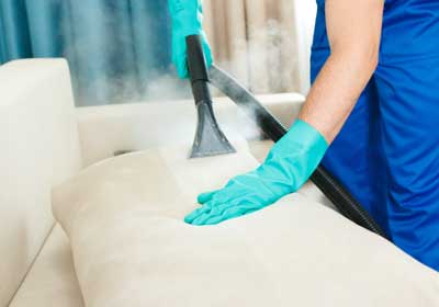 Gloved hands steam cleaning mattress