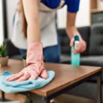 A Texas homeowner wiping down their coffee table after spraying it with cleaning solution