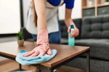 A Texas homeowner wiping down their coffee table after spraying it with cleaning solution