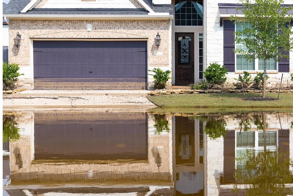 A suburban home struggling with floodwater that's covering their driveway.